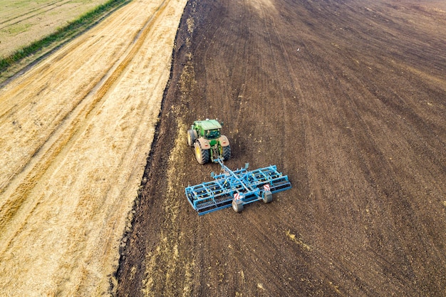 Vista aérea de un tractor arando el campo de granja agrícola negro a finales de otoño.