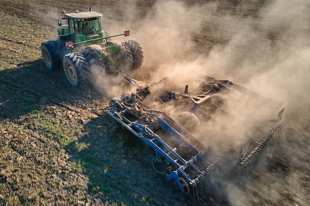 Vista aérea del tractor arando el campo de la granja agrícola preparando el suelo para sembrar en verano