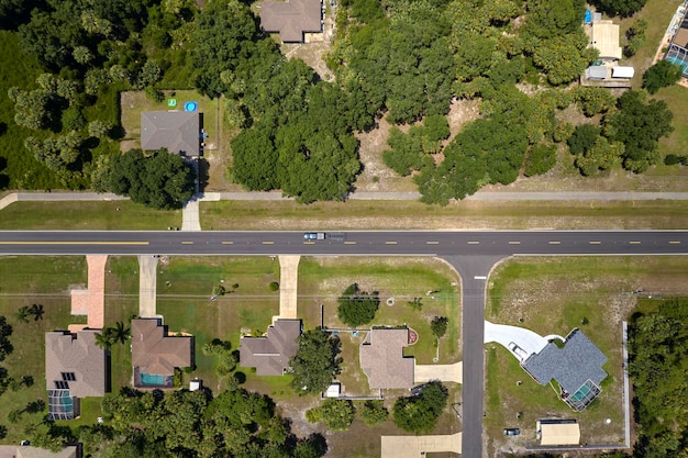 Vista aérea del tráfico de la calle con coches de conducción en un pequeño paisaje suburbano estadounidense con casas privadas entre palmeras verdes en la tranquila zona residencial de Florida