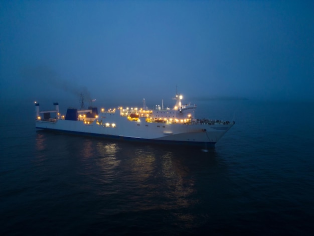 Vista aérea de un transbordador que navega a través de condiciones de niebla en la noche en el mar