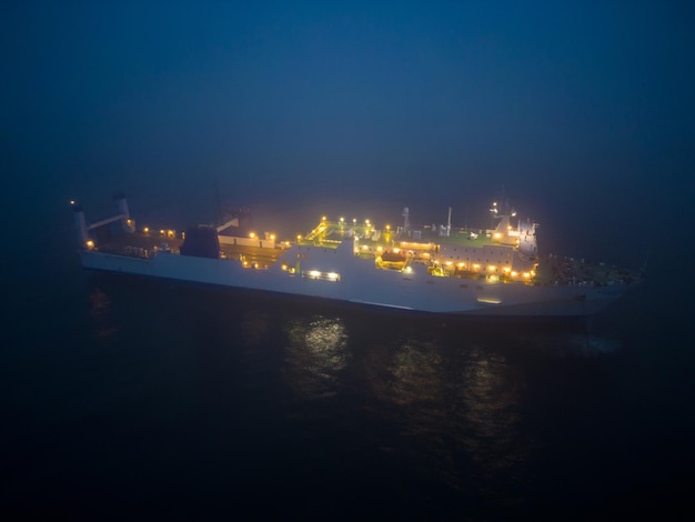 Vista aérea de un transbordador que navega a través de condiciones de niebla en la noche en el mar