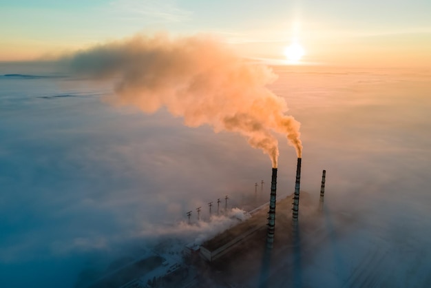 Vista aérea de las tuberías altas de la planta de energía de carbón con humo negro que sube por la atmósfera contaminante al amanecer