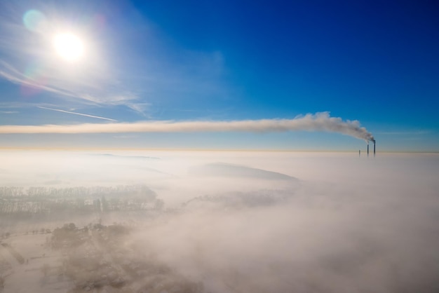 Vista aérea de las tuberías altas de la planta de energía de carbón con humo negro que sube por la atmósfera contaminante al amanecer