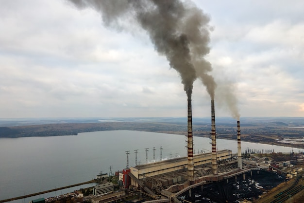 Vista aérea de los tubos altos de la planta de energía de carbón con humo negro subiendo la atmósfera contaminante.