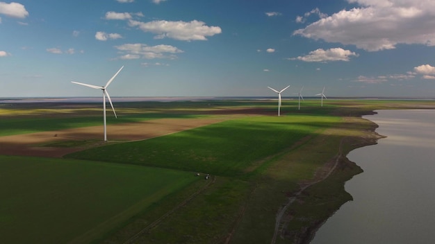 Vista aérea de turbinas eólicas y campo agrícola cerca del mar al atardecer