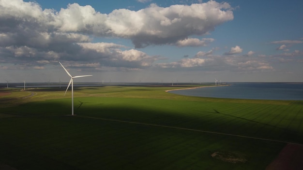 Vista aérea de turbinas eólicas y campo agrícola cerca del mar al atardecer