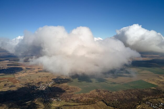 Foto vista aérea desde la ventana de un avión a gran altitud de la tierra cubierta de nubes cumulus hinchadas blancas