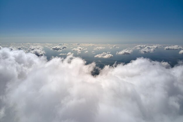 Vista aérea desde la ventana del avión a gran altura de la tierra cubierta de cúmulos hinchados que se forman antes de la tormenta.