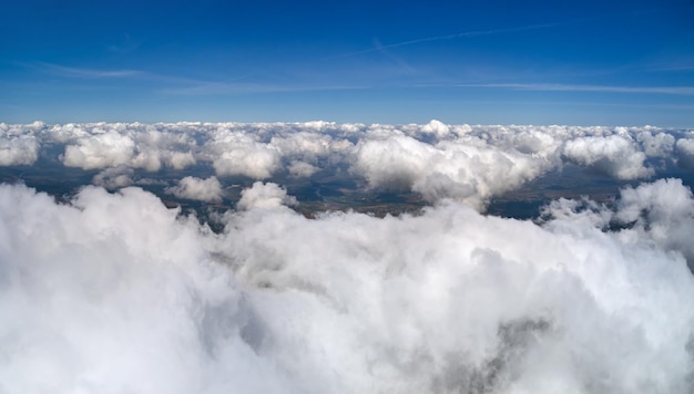 Vista aérea desde la ventana del avión a gran altura de la tierra cubierta de cúmulos hinchados que se forman antes de la tormenta