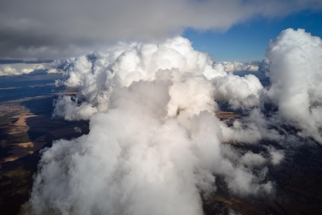 Vista aérea desde la ventana del avión a gran altura de la tierra cubierta de cúmulos hinchados que se forman antes de la tormenta