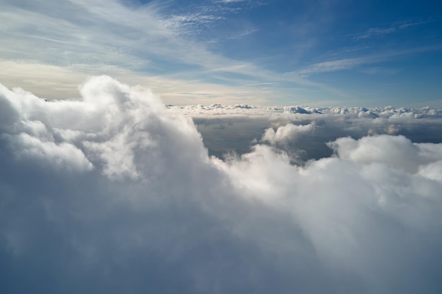 Vista aérea desde la ventana del avión a gran altura de la tierra cubierta de cúmulos hinchados que se forman antes de la tormenta