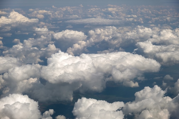 Vista aérea desde la ventana del avión de nubes blancas en un día soleado.