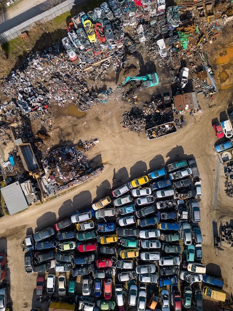 Vista aérea de un vertedero de automóviles donde se ve una máquina separando autos viejos en chatarra