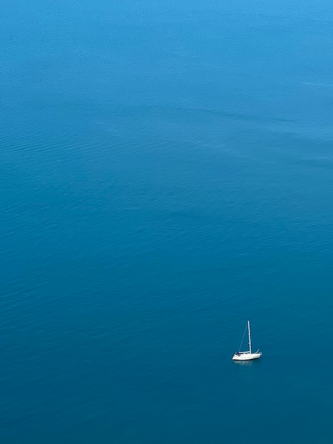 Foto vista aérea de un yate blanco con una vela buque en el mar azul