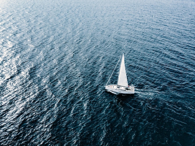 Vista aérea de yates de veleros con velas blancas en condiciones de viento en el mar azul profundo