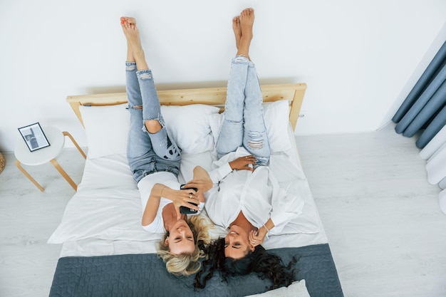 Vista al revés Acostada en la cama Dos mujeres están juntas en casa