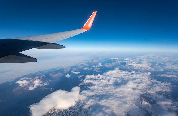 Vista del ala del avión, las nubes y el cielo visto a través de la ventana de la aeronave