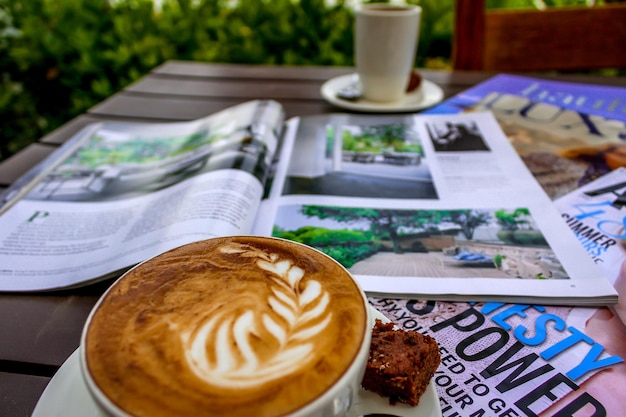 Vista de alto ángulo de capuchino y revistas en la mesa en el patio
