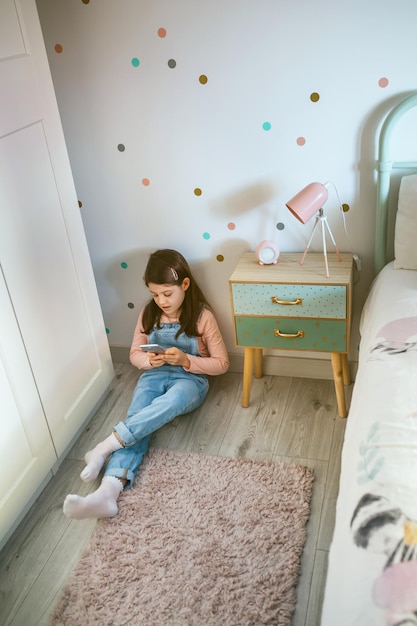 Foto vista de alto ángulo de una chica usando un teléfono móvil sentada en casa