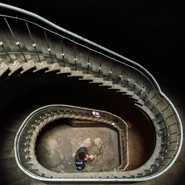 Foto vista de alto ángulo de la escalera de caracol con el hombre de pie