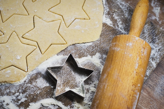 Vista de alto ángulo de galletas en forma de estrella con rodillo y cortador en la mesa