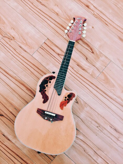 Foto vista de alto ángulo de una guitarra acústica en un piso de madera