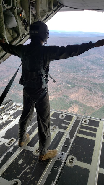 Foto vista de alto ángulo de un hombre de pie en la rampa de un avión militar en vuelo