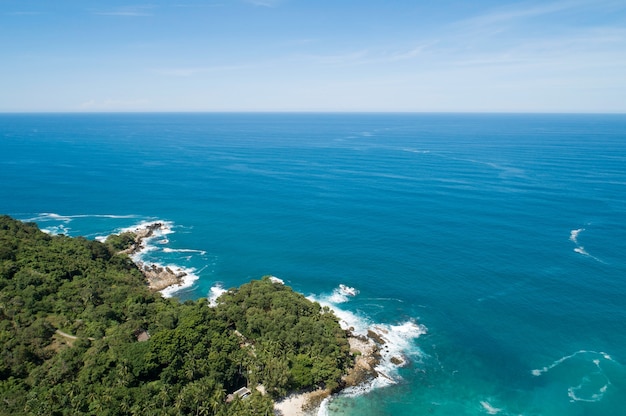 Vista de alto ángulo Mar tropical con olas rompiendo en la orilla del mar y alta montaña ubicada en Phuket Tailandia vista aérea drone de arriba hacia abajo Paisaje de vista de naturaleza increíble Hermosa superficie del mar.