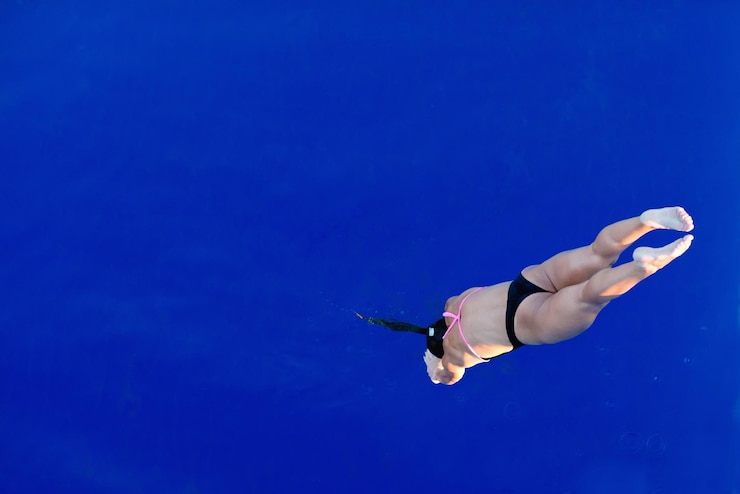 Foto vista de alto ángulo de una mujer adulta con bikini mientras salta en la piscina