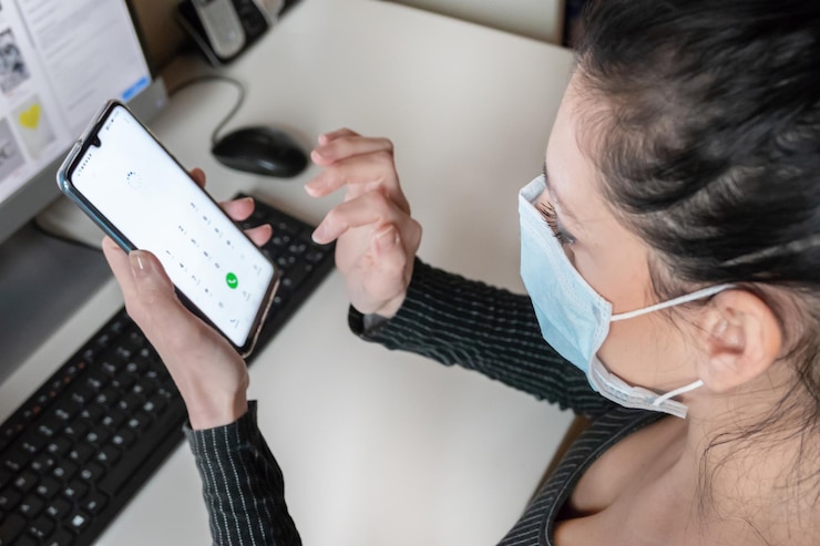 Foto vista de alto ángulo de una mujer con máscara usando un teléfono móvil