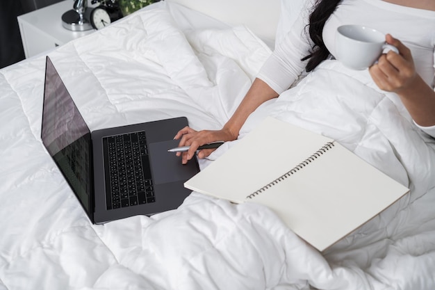 Vista de alto ángulo de una mujer usando una computadora portátil en la cama