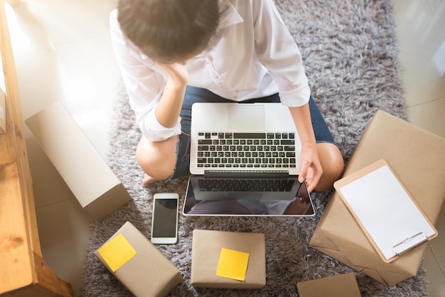 Vista de alto ángulo de una mujer usando una computadora portátil mientras está sentada en el suelo