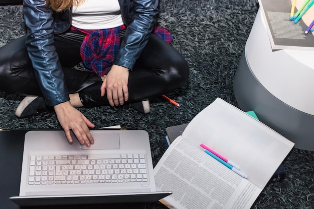 Vista de alto ángulo de una mujer usando una computadora portátil mientras está sentada en el suelo