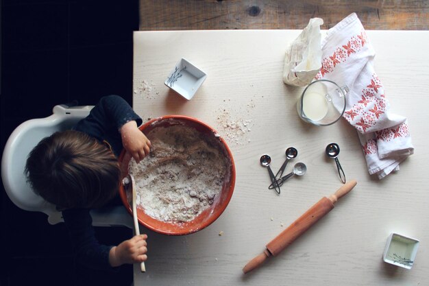 Foto vista de alto ángulo de un niño jugando con comida en la mesa en casa