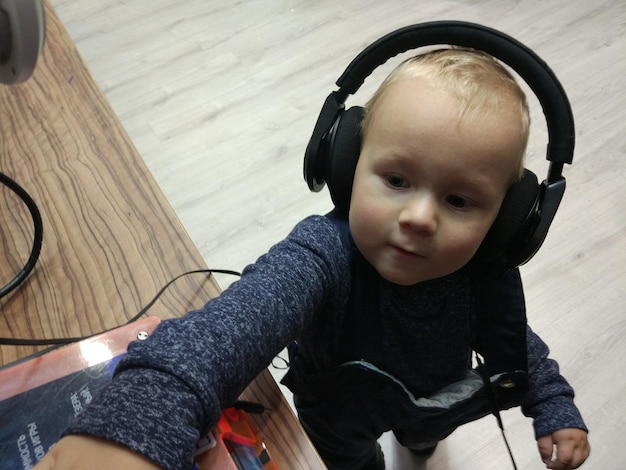 Vista de alto ángulo de un niño lindo escuchando música con auriculares en casa