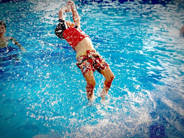 Foto vista de alto ángulo de un niño saltando en la piscina