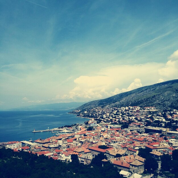 Foto vista de alto ángulo del paisaje de la ciudad por el mar contra el cielo