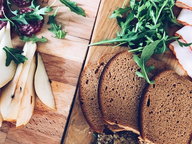 Vista de alto ángulo de pan y variedad de alimentos sabrosos en tablas de cortar de madera