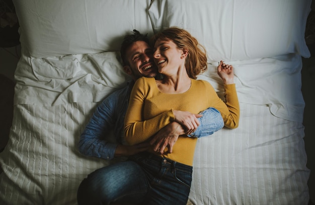 Vista de alto ángulo de una pareja abrazada mientras está acostada en la cama en casa