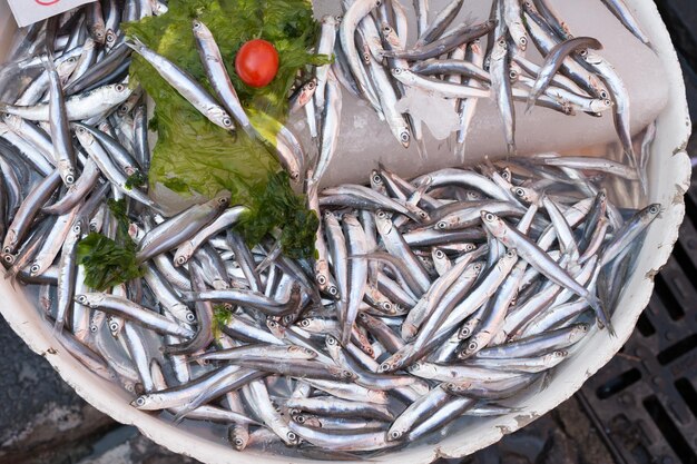 Vista de alto ángulo de peces frescos y hojas en bandeja en el mercado