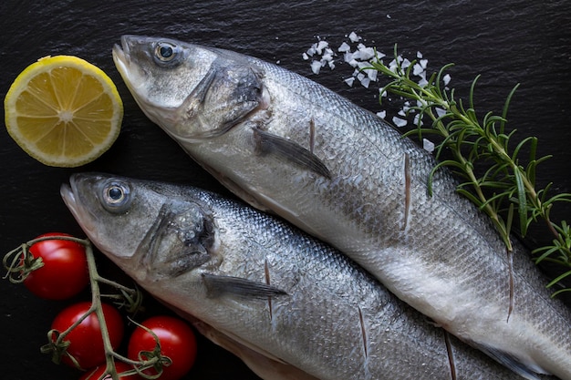 Vista de alto ángulo de peces con ingredientes en pizarra