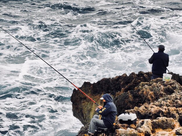 Foto vista de alto ángulo de personas pescando en el mar en rocas