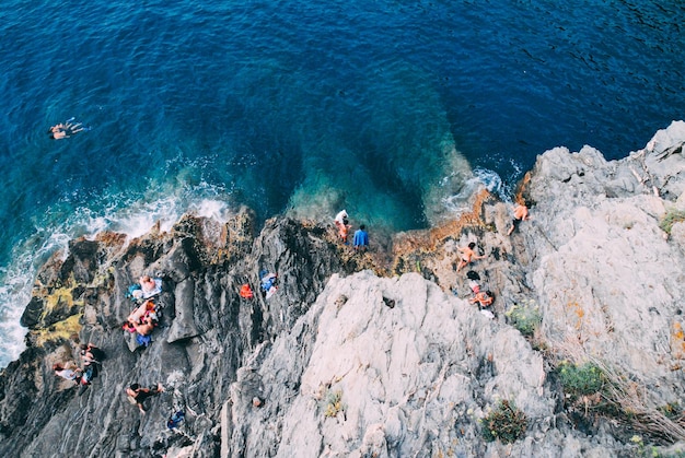 Vista de alto ángulo de personas en rocas junto al mar