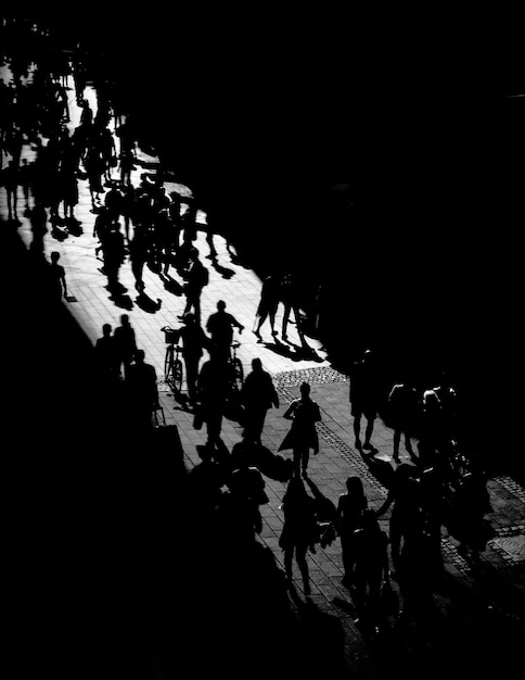 Vista de alto ángulo de personas en silueta caminando por la calle por la noche