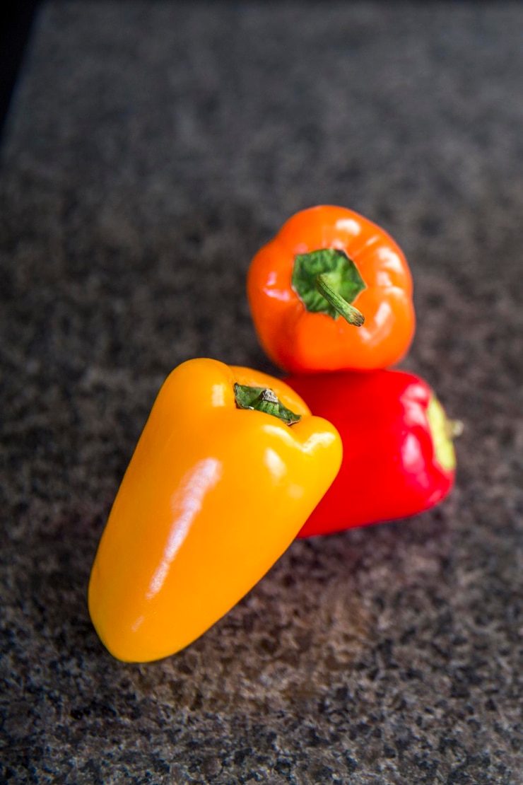 Foto vista de alto ángulo de pimientos amarillos rojos naranjas sobre fondo negro
