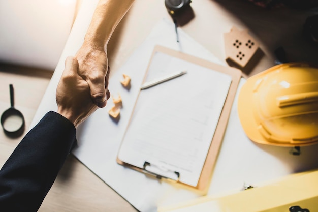 Vista de alto ángulo de primer plano de un hombre de negocios y un arquitecto estrechando la mano en la oficina