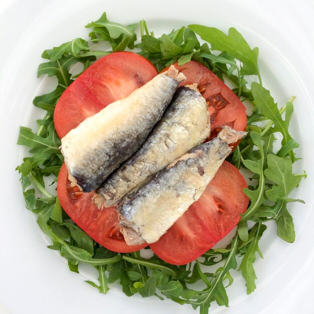 Foto vista de alto ángulo de sardinas sobre ensalada en el plato