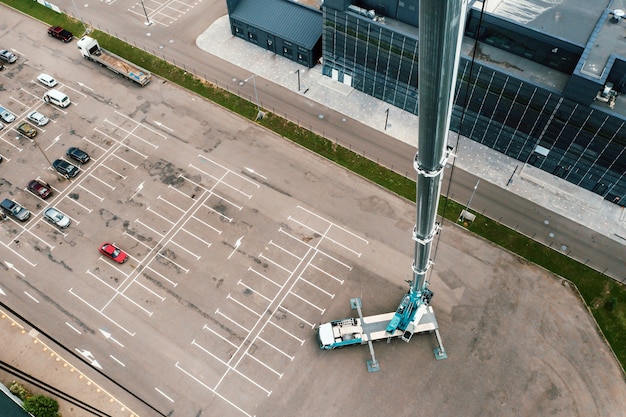 Vista desde la altura de la grúa pesada Car que está abierta en el estacionamiento y lista para trabajar. el camión grúa más alto se despliega en el sitio. la altura de la pluma es de 80 metros