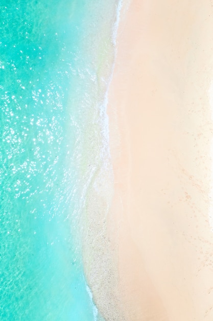 Una vista desde la altura de una playa tropical y olas rompiendo en una playa tropical de arena dorada. Las olas del mar se mueven suavemente a lo largo de la hermosa playa de arena.