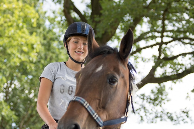 Foto vista en bajo ángulo de un adolescente feliz montando un caballo